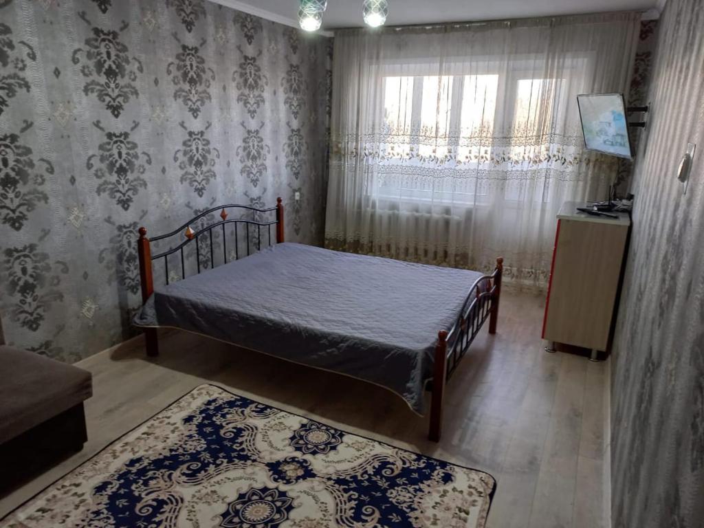 Комфортные аппартаменты في كاراغاندي: غرفة نوم صغيرة بها سرير ونافذة