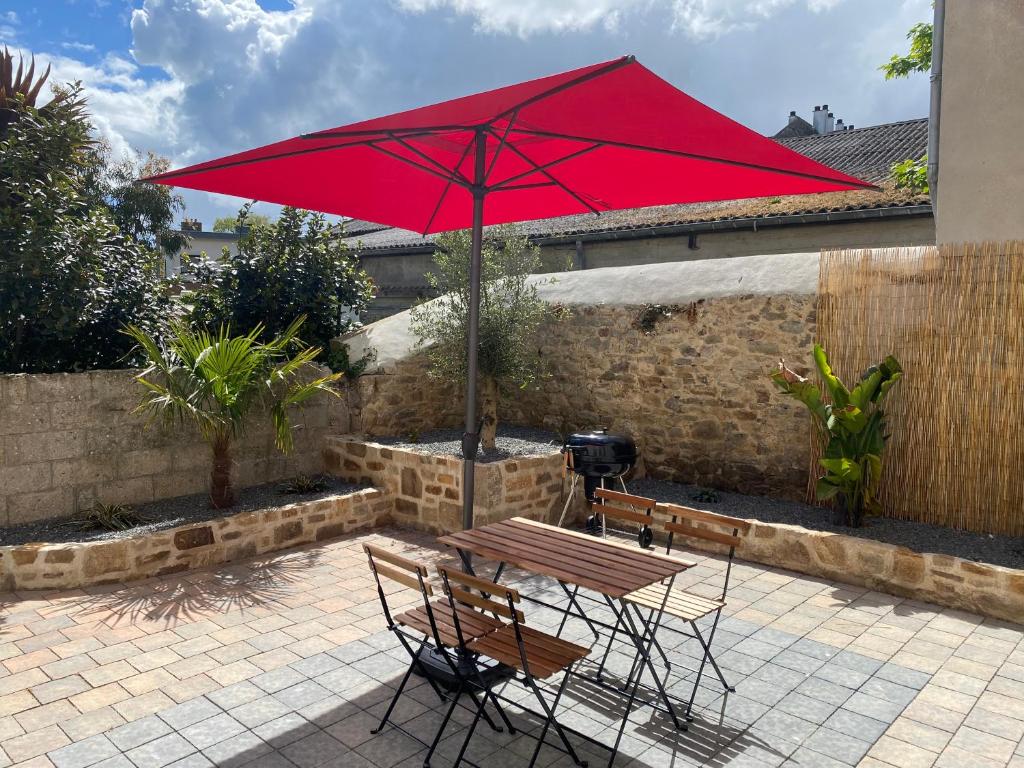 - une table de pique-nique avec un parasol rouge sur la terrasse dans l'établissement Résidence de la Poste, à Saint-Pol-de-Léon