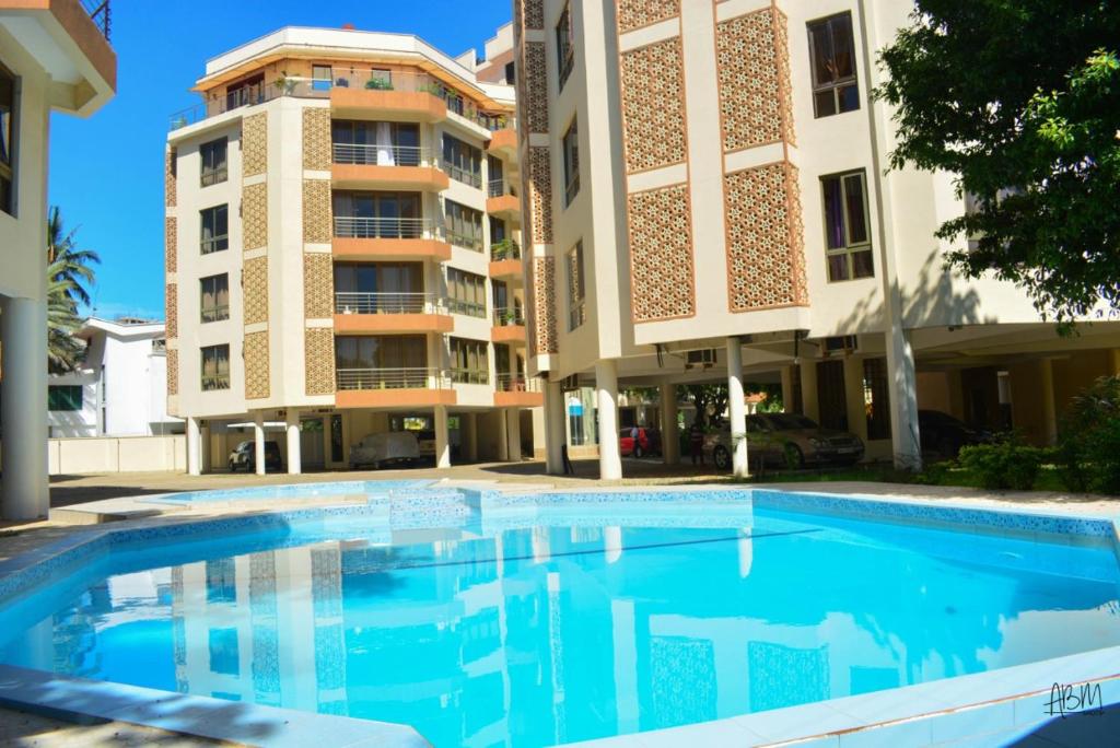 a swimming pool in front of a building at Danmic in Mombasa