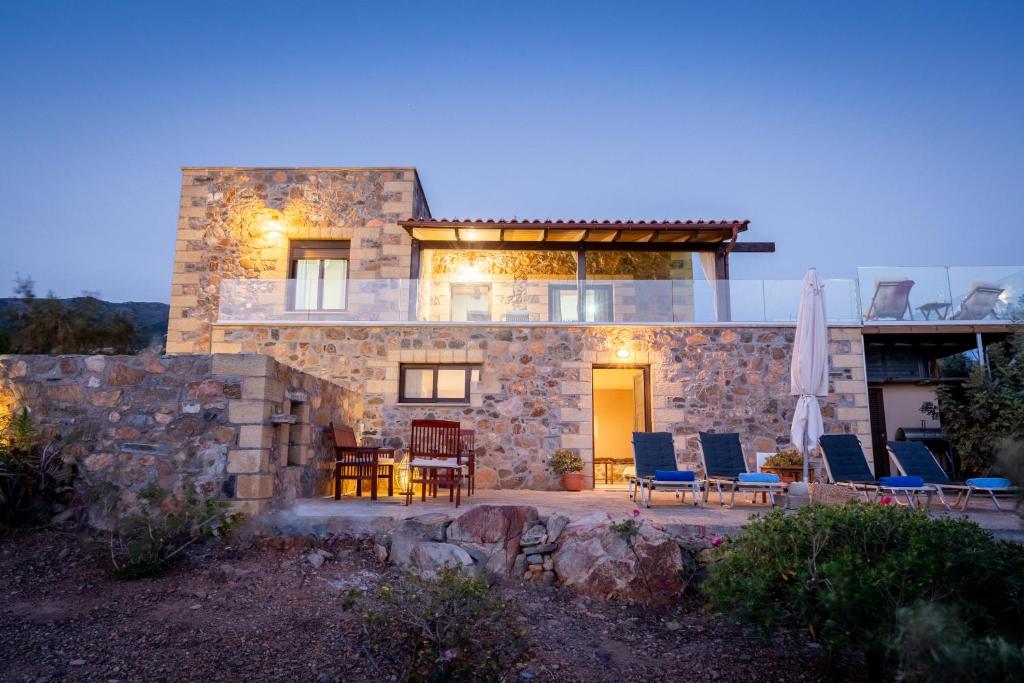 ein Steinhaus mit Stühlen und einem Tisch in der Unterkunft Blue Pearl Villa in AmigdhalokeFálion