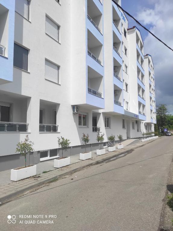 eine leere Straße vor einem weißen Apartmenthaus in der Unterkunft Апартман Милица in Banja Koviljača