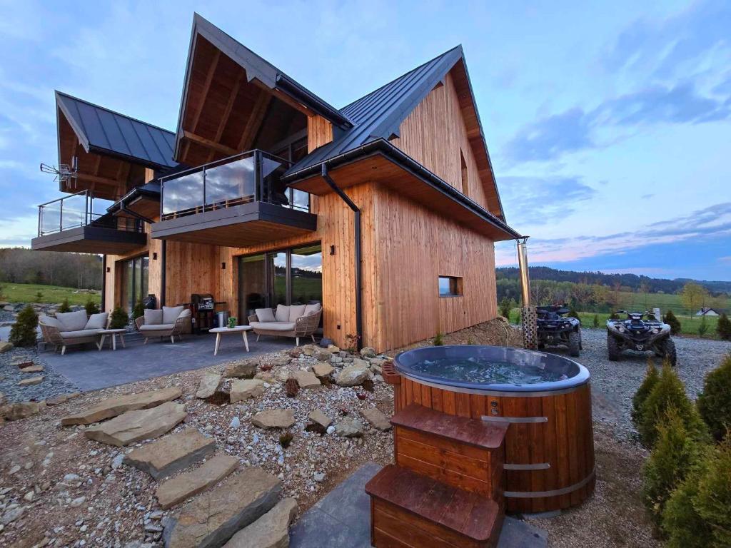 a wooden house with a hot tub in the yard at Vidokówka Resort in Waksmund