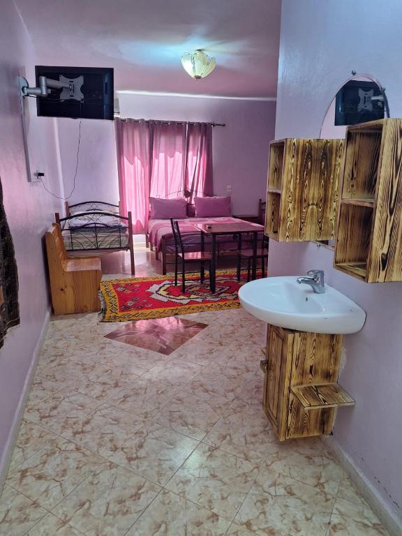 a bathroom with a sink and a living room at Maison Touria in Ouzoud