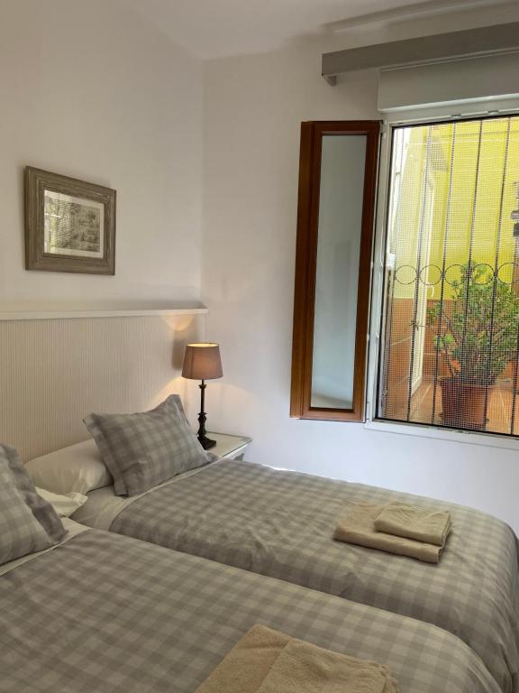 two beds in a room with a window at PLENO CENTRO COMILLLAS-3 Hab, 2 Baños in Comillas