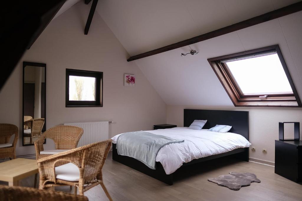 a bedroom with a bed and a window and chairs at Domaine du fil de l'eau in Watten