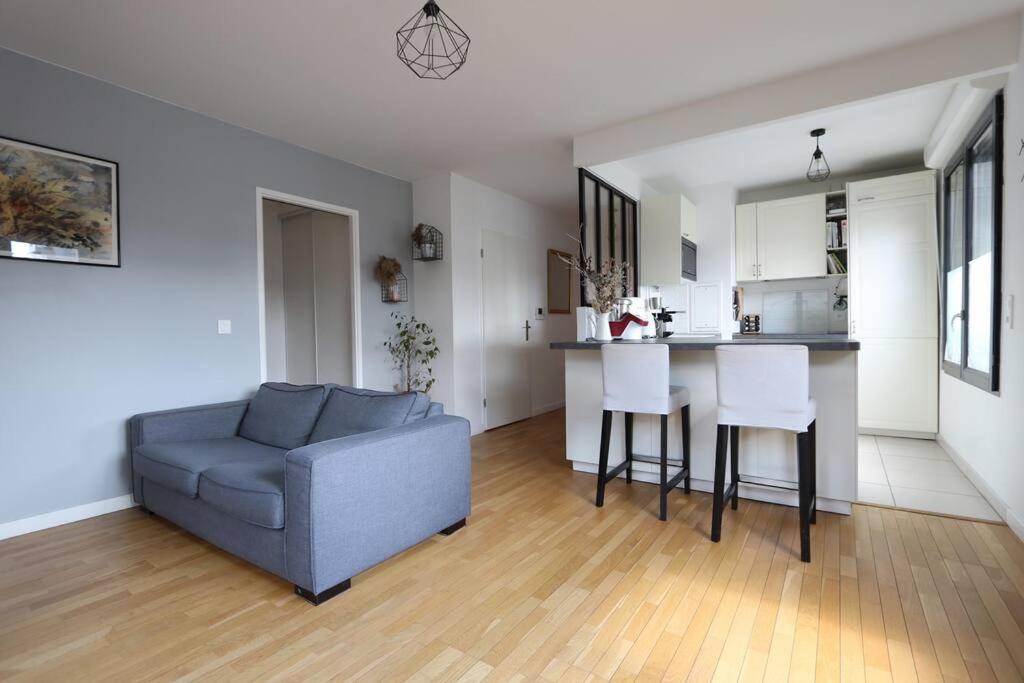 sala de estar con sofá, mesa y cocina en Appartement calme et lumineux proche Paris, en Asnières-sur-Seine