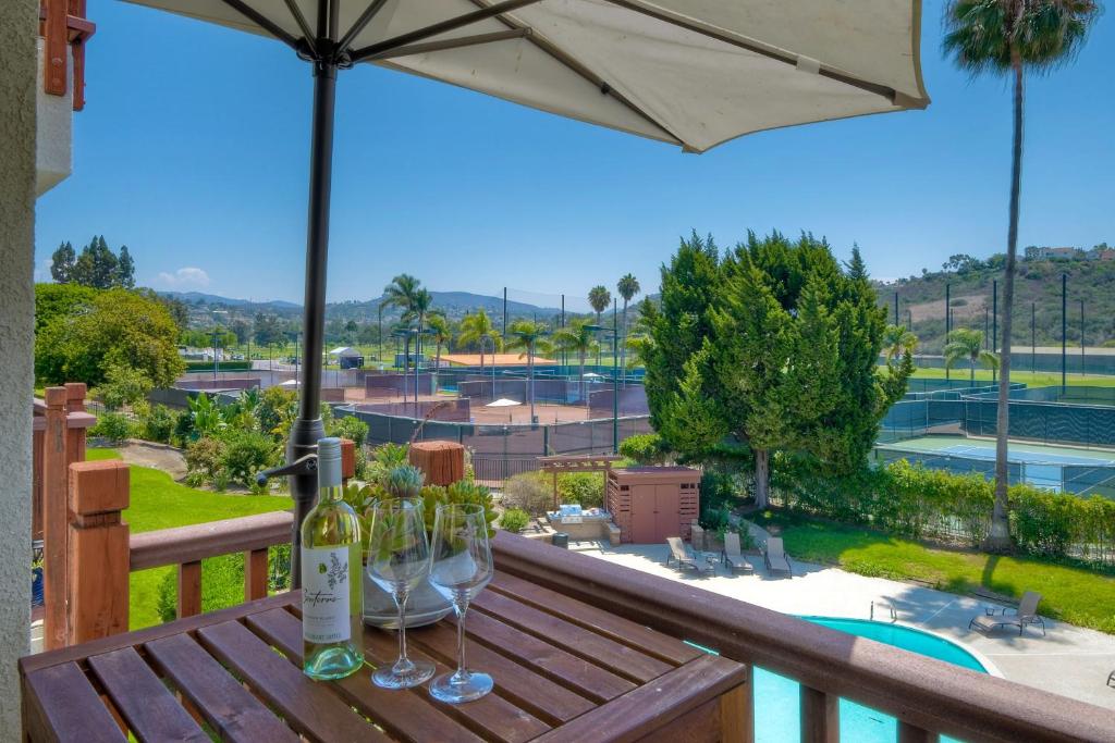 a table with wine glasses and an umbrella on a balcony at Beautifully Remodeled - Private Balcony - Pool View - BBQ Access - Gated Reserved Parking in Encinitas