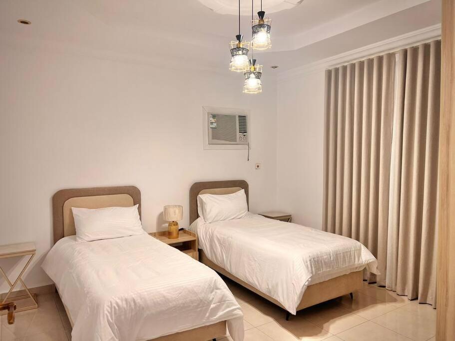 2 camas en una habitación con paredes y cortinas blancas en Rawda 2 Bed-Room Apartment in Jeddah, 100 meter to supermarket en Yeda