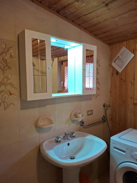 y baño con lavabo y espejo. en Falcade Dolomiti La Quiete Mansarda panoramica, en Fregona