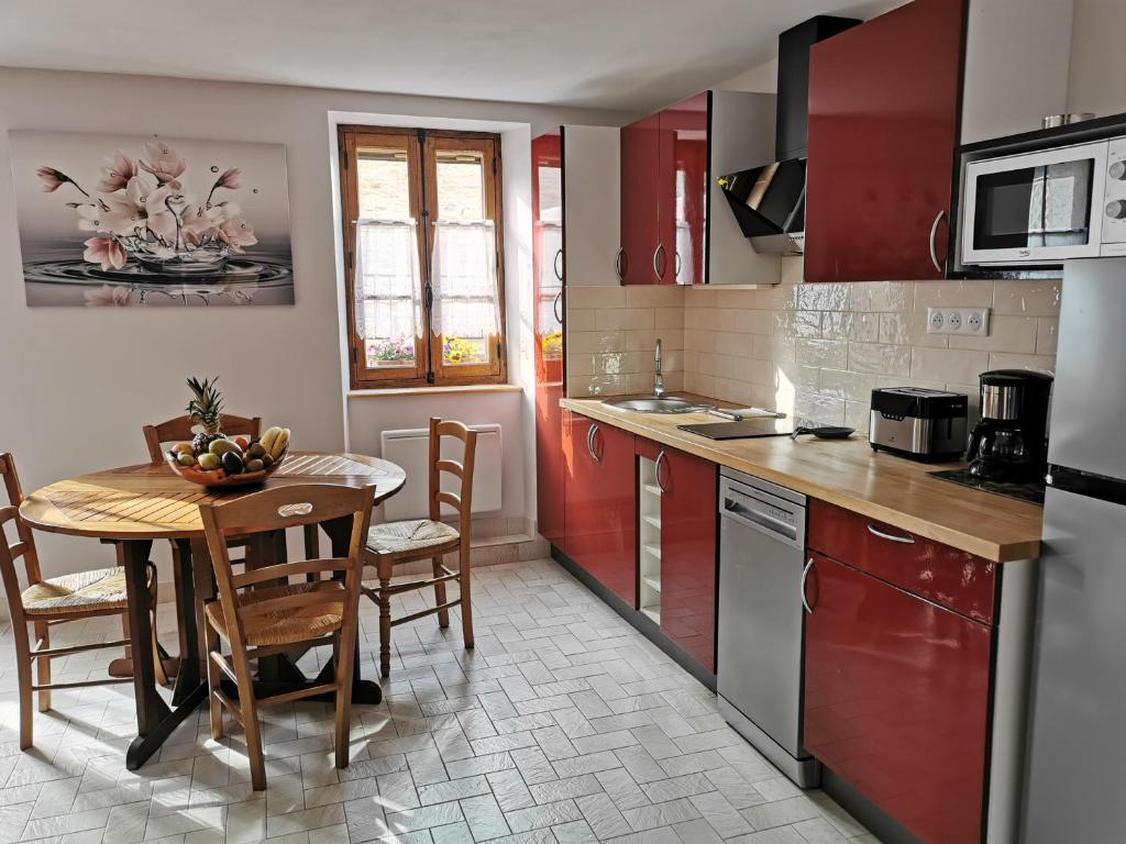 a kitchen with red cabinets and a table and chairs at Le studio de Josephine in Blars