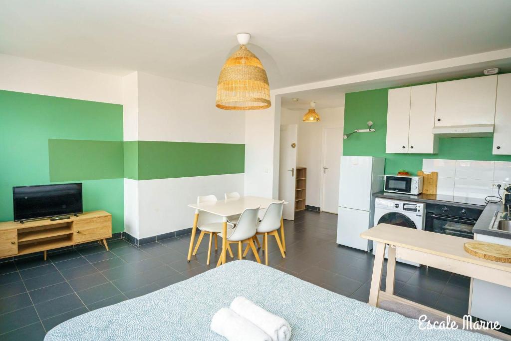 a kitchen and dining room with a table and chairs at escale-marne fr - 21 - Appartement entier, 4 pers, 10mn metro 8, RER A, Parking rue Gratuit, Grand Matelas Emma, Cuisine Équipée, Vue panoramique, 2ème étage in Maisons-Alfort
