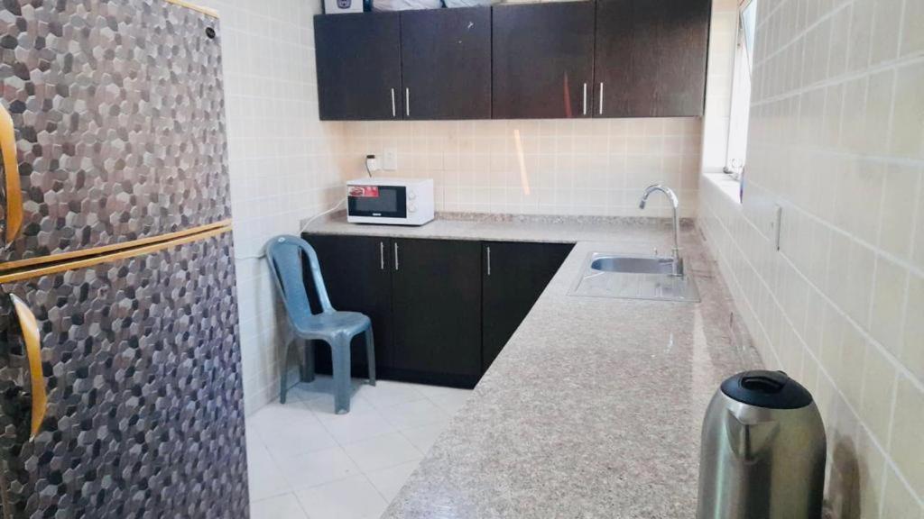 eine kleine Küche mit einem Waschbecken und einem blauen Stuhl in der Unterkunft Couples Loft Partition CLOSE to MALL OF EMIRATES METRO in Dubai