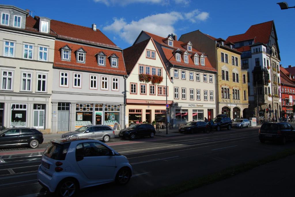 ein weißes Auto, das eine Stadtstraße mit Gebäuden entlangfährt in der Unterkunft B2-Ferienwohnung in Erfurt