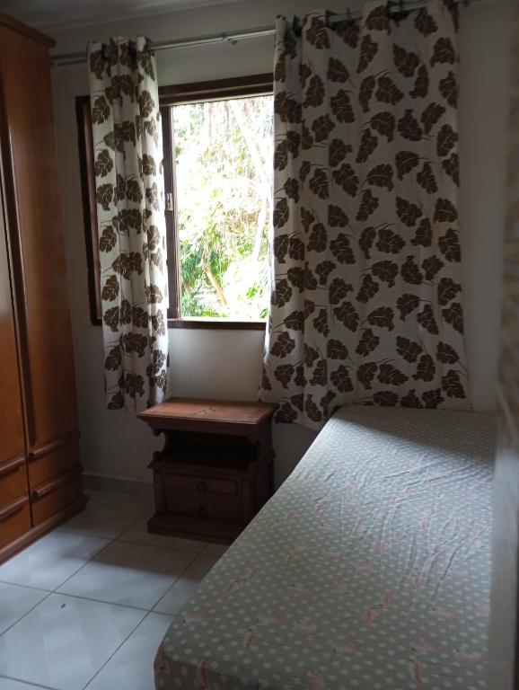 a bedroom with a bed and a window with curtains at Casa famíliar agradável in Rio de Janeiro