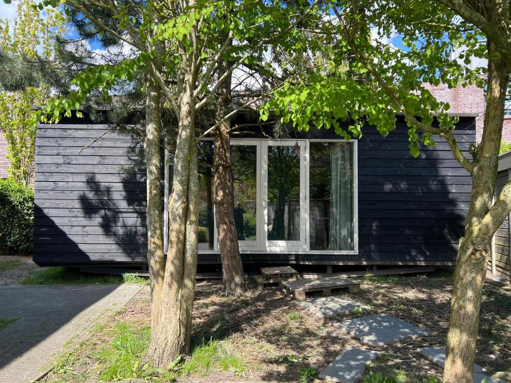 uma casa negra com árvores em frente em A tiny house close to nature - Amsterdam region em Lelystad