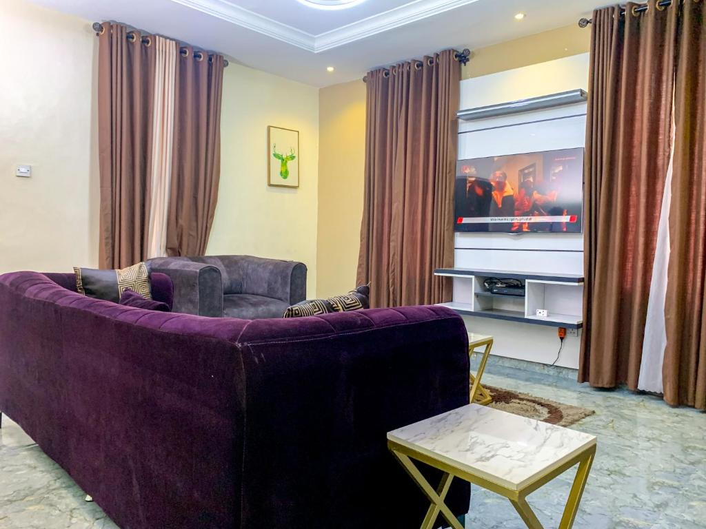 sala de estar con sofá púrpura y TV en 28B (3/2B), en Lagos