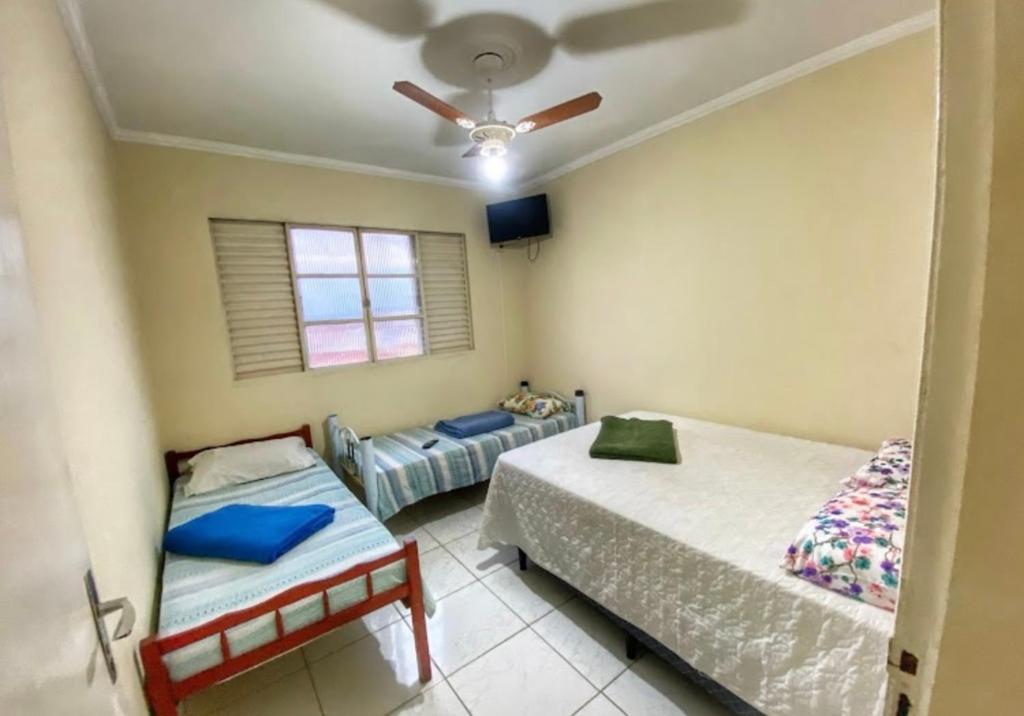 a bedroom with two beds and a ceiling fan at Casarão Hostel in Guaratinguetá