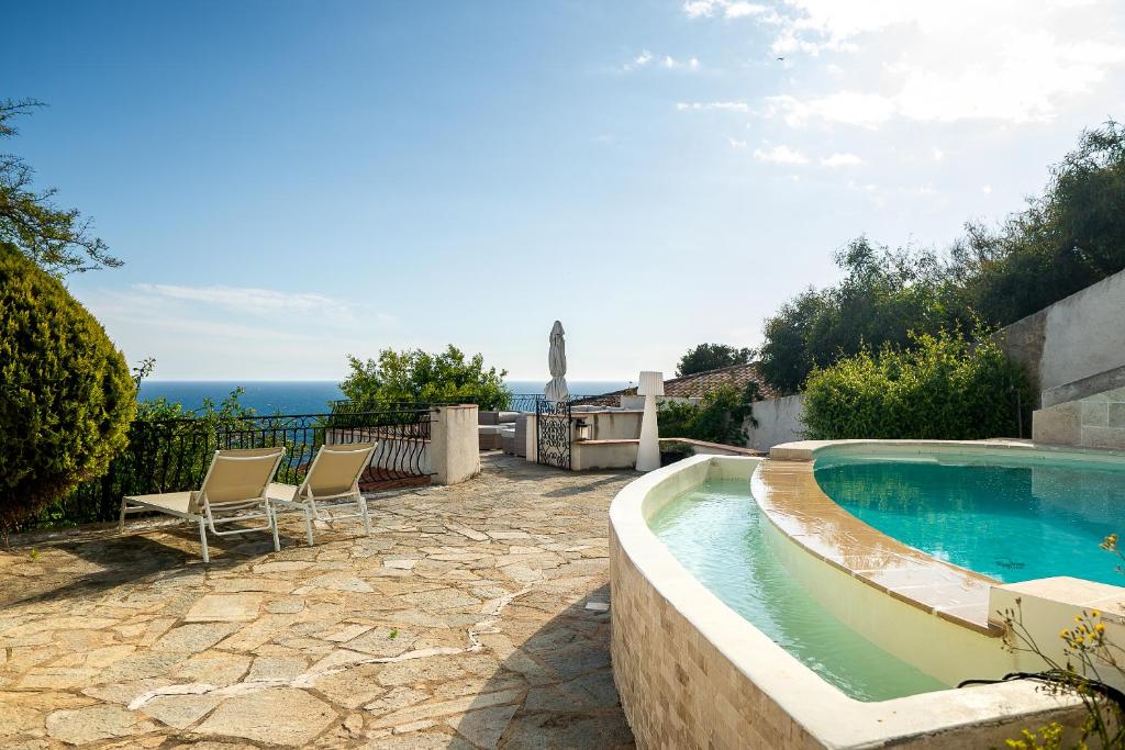 a swimming pool with two chairs and the ocean in the background at Villa prestige (voiture plage) in Carqueiranne