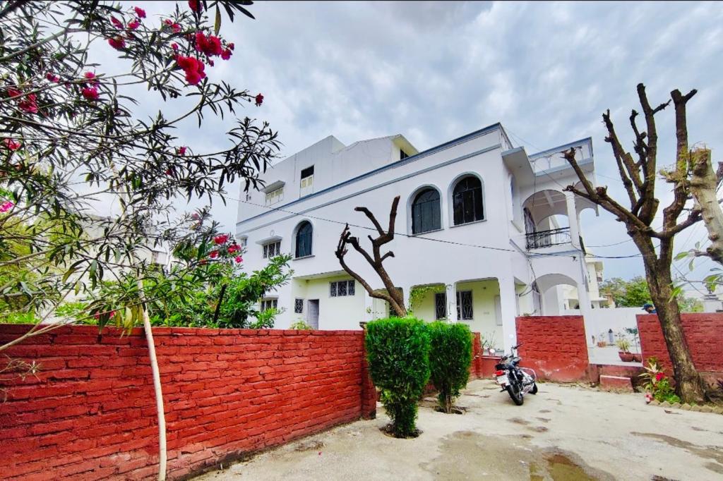 una casa blanca con una valla de ladrillo rojo y una motocicleta en Boho Heritage Stays Udaipur, en Udaipur