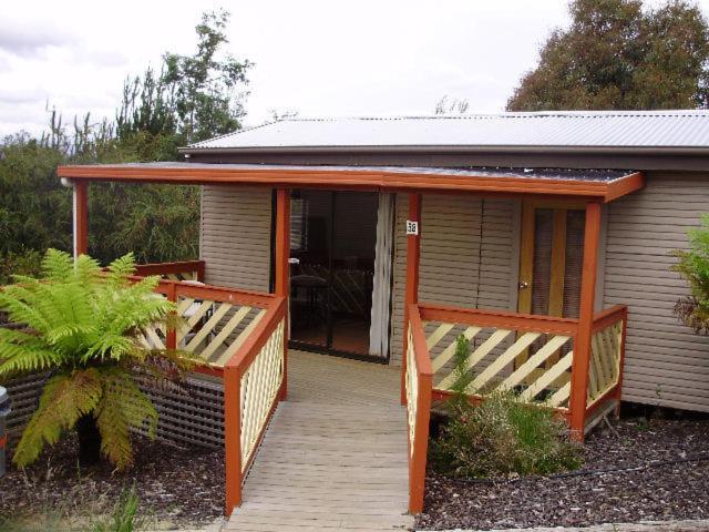 een klein huis met een veranda en een houten terras bij Launceston Holiday Park Legana in Legana