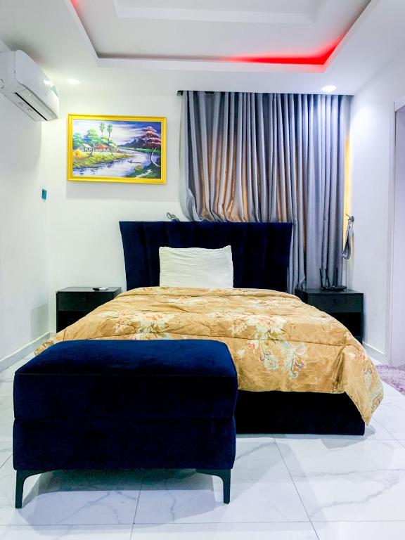 a bedroom with a large bed with a blue ottoman at 60B Adetoun Adelaja 4Bedroom in Lagos