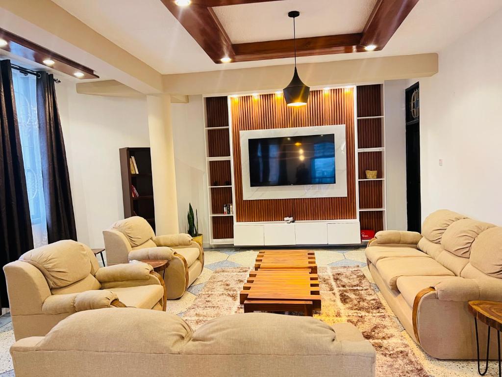 a living room with couches and a flat screen tv at Urban Haven Rooms in Iringa