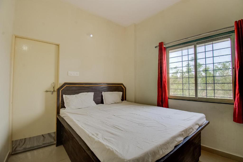 - une chambre avec un grand lit et des rideaux rouges dans l'établissement SPOT ON San Tower Hotel, à Kilimanūr