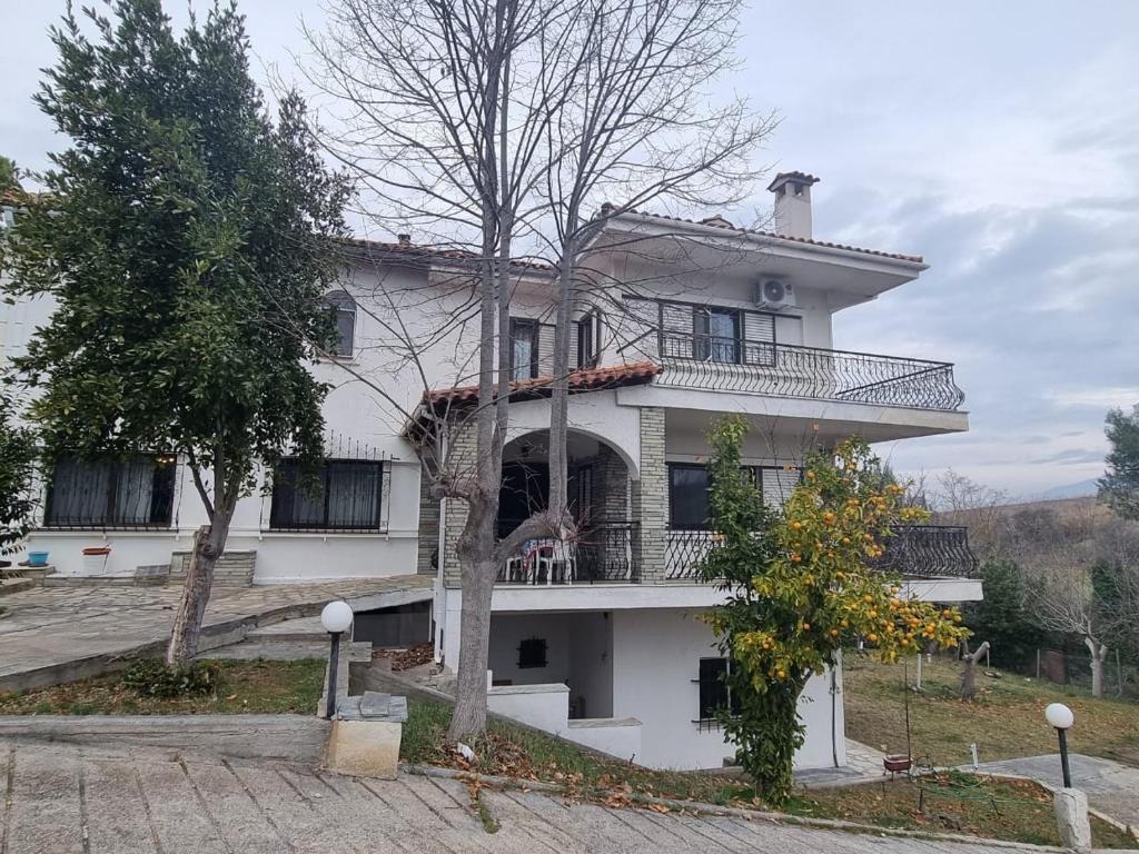 a white house with a balcony and a tree at Villa in Trilofos-close to the beach in Thessaloniki