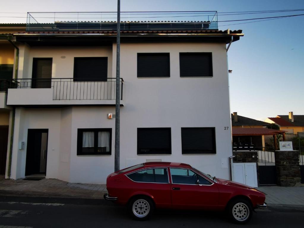 een rode auto geparkeerd voor een wit gebouw bij CASA FLIPE t2 in Bragança