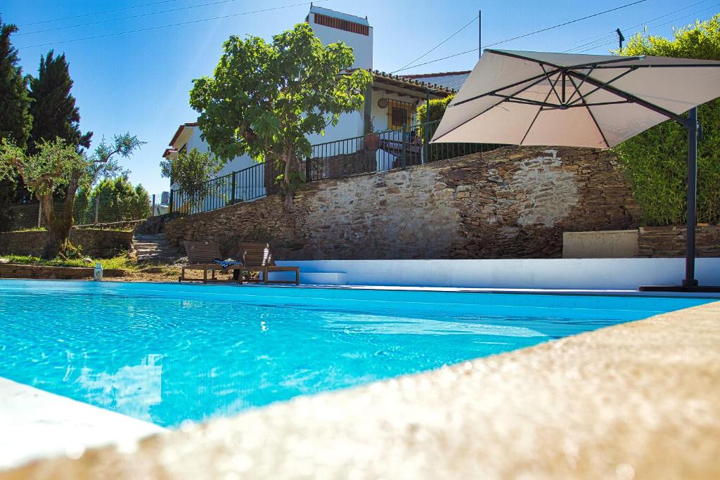 - une piscine avec un parasol à côté d'une maison dans l'établissement Monte Alecrim, à Alandroal