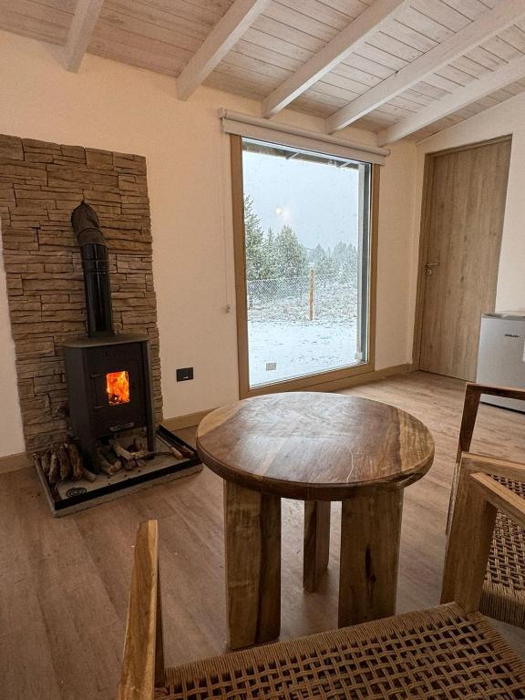 a living room with a table and a fireplace at Cabaña El Galpón - Villa Meliquina - in Lago Meliquina