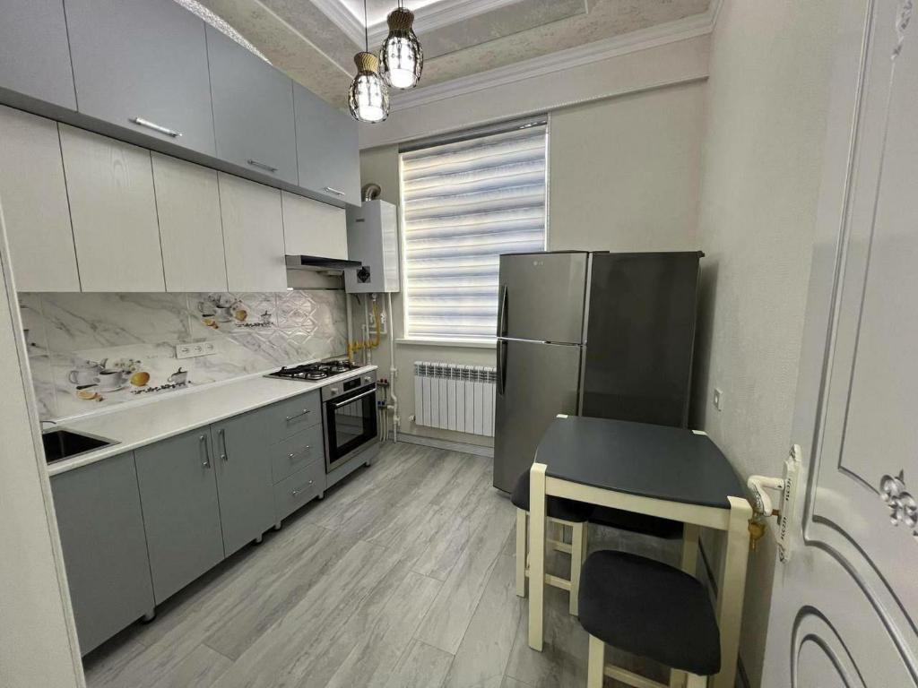 a kitchen with white cabinets and a black refrigerator at Comfort House in Tashkent