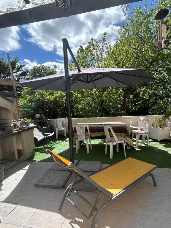 a patio with an umbrella and a table and chairs at PARENTHÈSE Chambre Cosy proche Centre et Gare in Angoulême