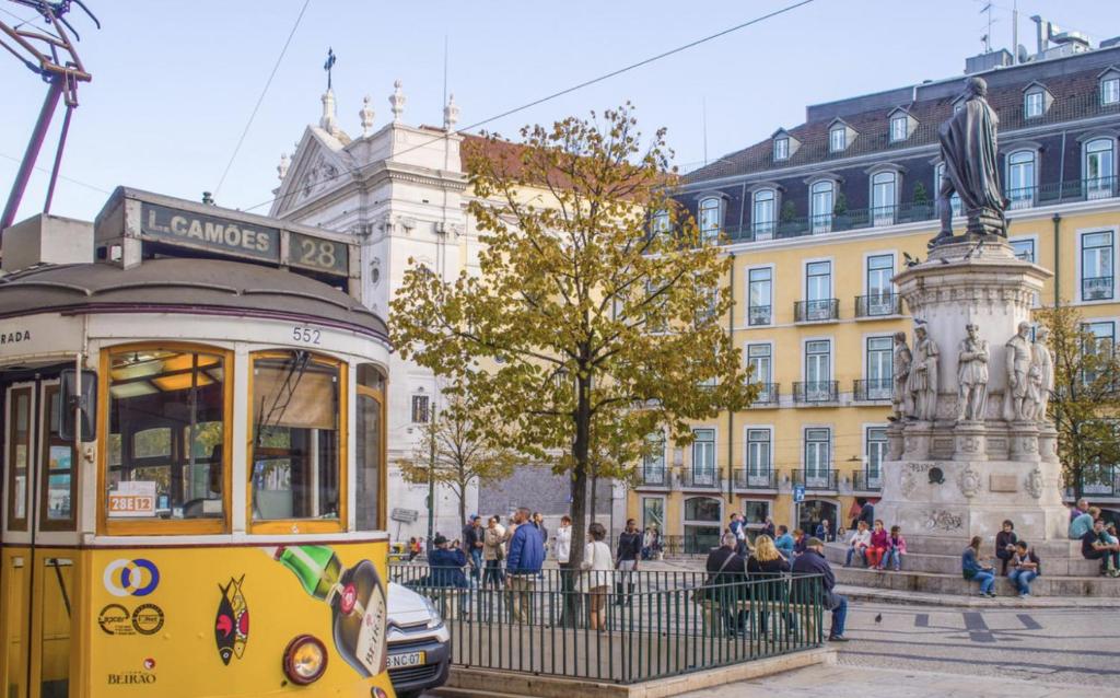 un tramway jaune devant un bâtiment dans l'établissement Mouraria - Apartamento, à Lisbonne