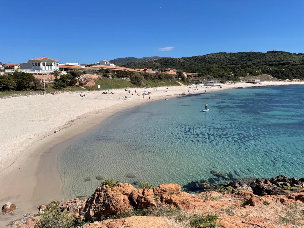 a beach with a group of people in the water at Casa I Corbezzoli - Paduledda - Isola Rossa in Cascabraga