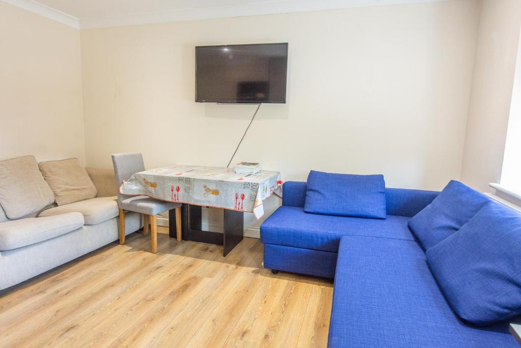 a living room with a blue couch and a table at Evergreen Apartments, Flat 3, London in London