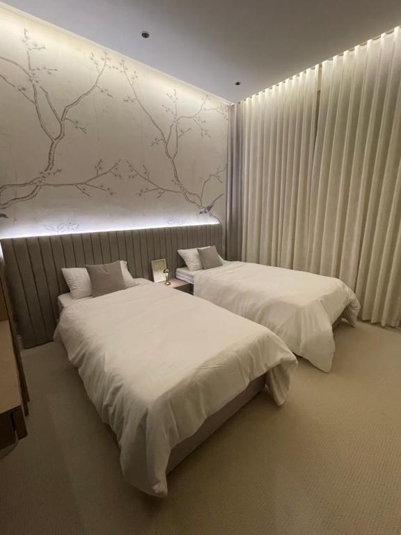 two beds in a room with white sheets at شقة فاخرة بمدخل طراز سلماني in Riyadh