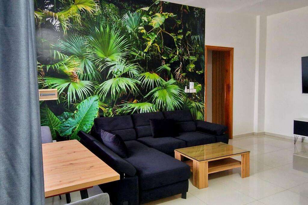 sala de estar con sofá negro y mesa en Jungle Sensation, en Lomé