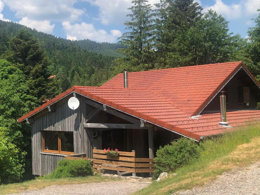 une grange avec un toit rouge sur une colline dans l'établissement Chalet confortable, proche des pistes de ski, avec jardin, terrasses couvertes et Wi-Fi à La Bresse - FR-1-589-86, à La Bresse