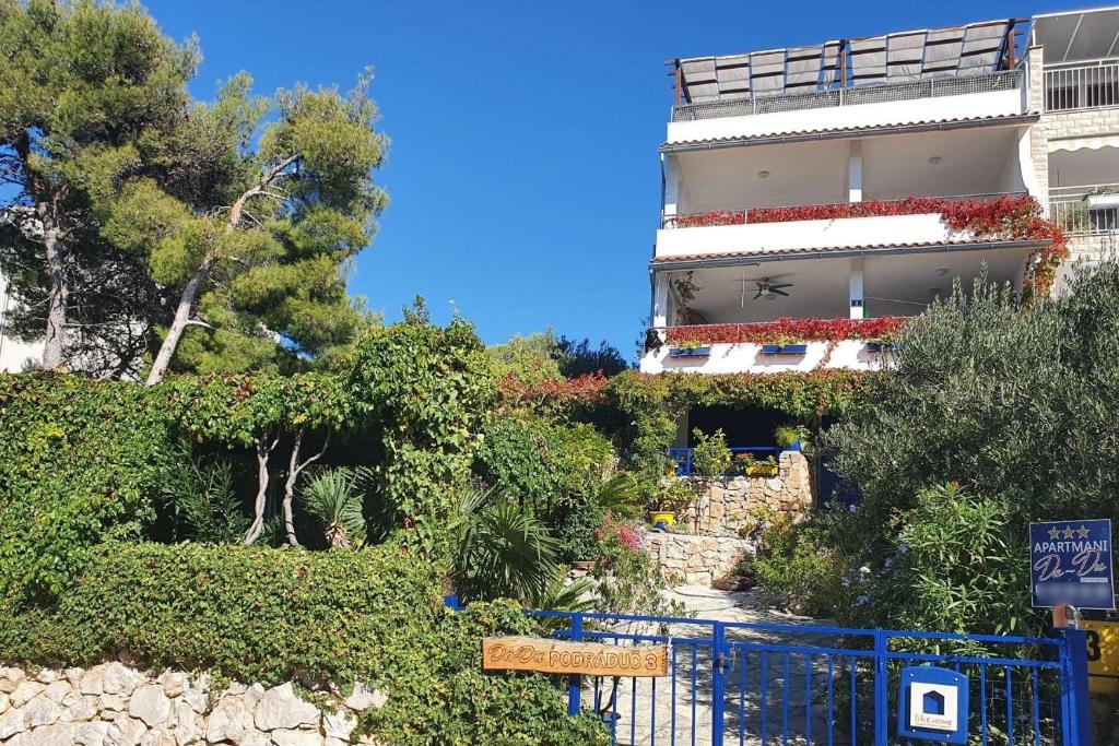 a building on a hill with bushes and trees at Apartments by the sea Murter - 22397 in Murter