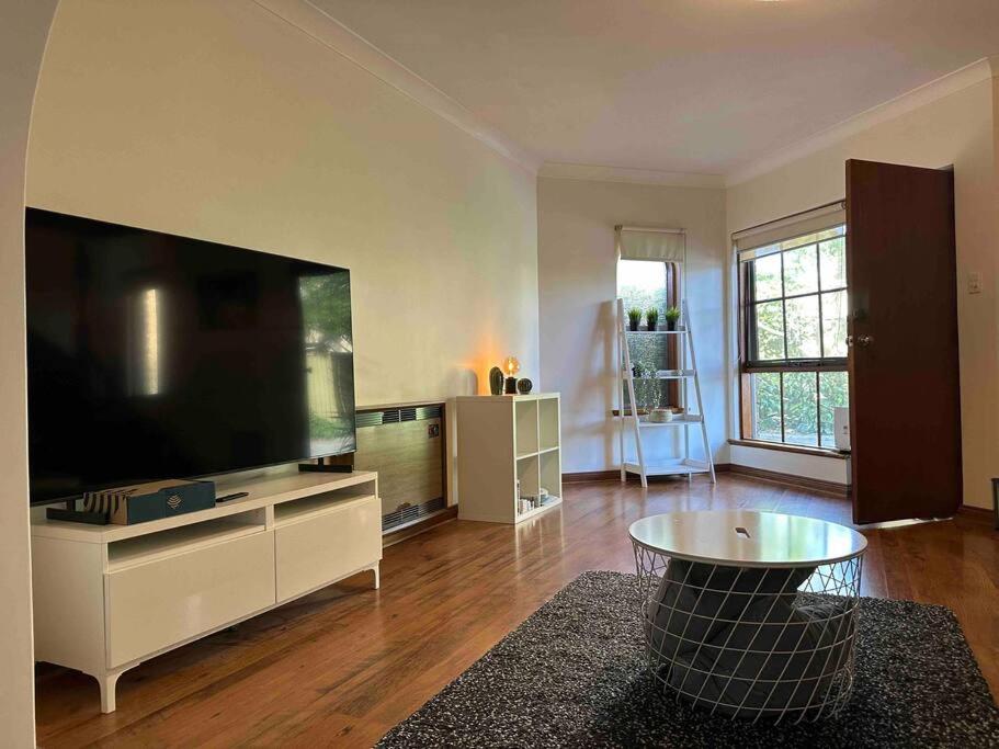 uma sala de estar com uma grande televisão de ecrã plano em Townhouse in heart of Glenelg em Glenelg
