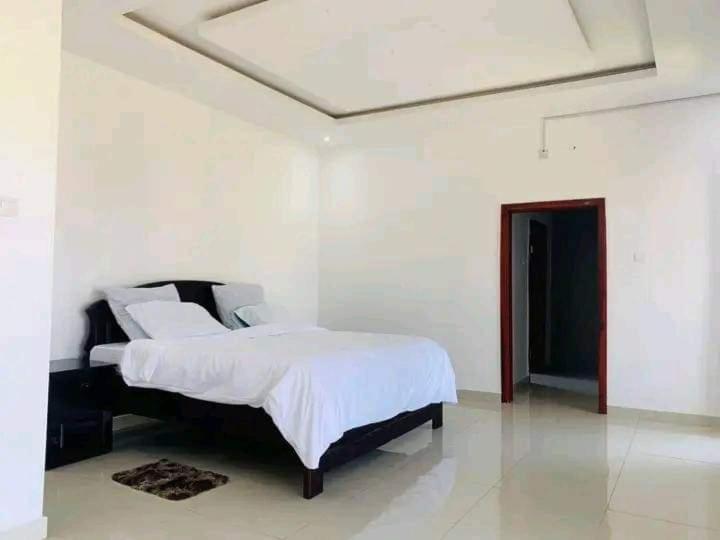 um quarto com uma cama num quarto branco em 2nd street home em Lusaka