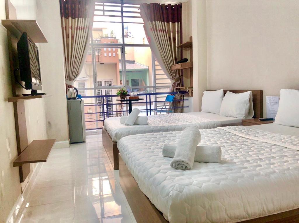 2 camas en una habitación con ventana grande en Thanhha Guesthouse, en Ho Chi Minh