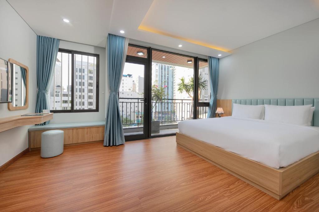 a bedroom with a large bed and large windows at Hummer Hotel & Apartment Da Nang Beach in Danang