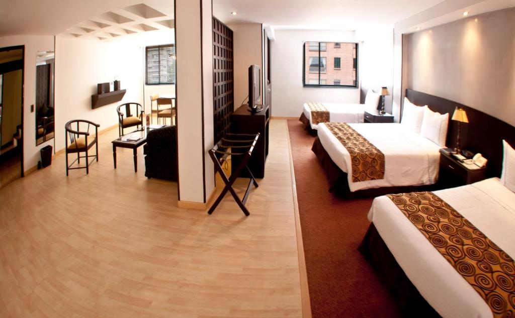 a hotel room with two beds and a living room at Centro Internacional Apartahotel in Bogotá