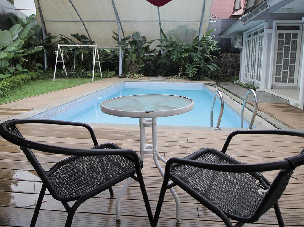 dos sillas y una mesa frente a una piscina en Diyar Villas Puncak M3/47, en Puncak