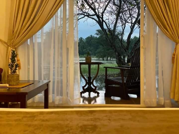 Habitación con mesa y ventana con cortinas. en Dhanwanthari Bhawan Ayurvedic Retreat, en Habarana