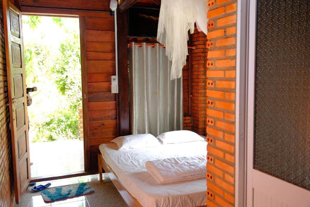 - une chambre avec un lit dans une pièce dotée d'une fenêtre dans l'établissement Du Nam Riverside Tour Trọn Gói, à Tân Phú