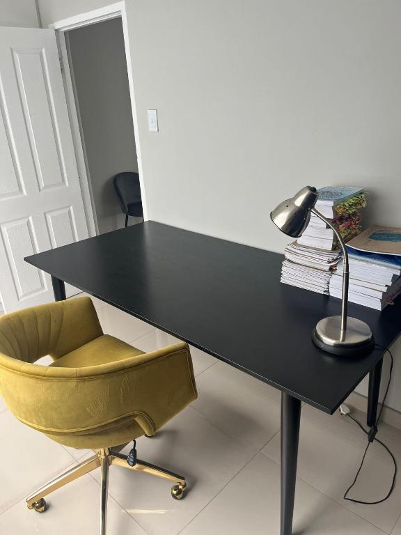 a black desk with a yellow chair and a lamp at 10 Glen Court in Durban