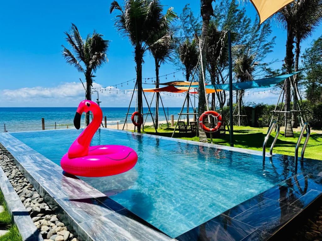 a swimming pool with a pink swan in the water at Whispering waves beachfront villa in Tiến Thành